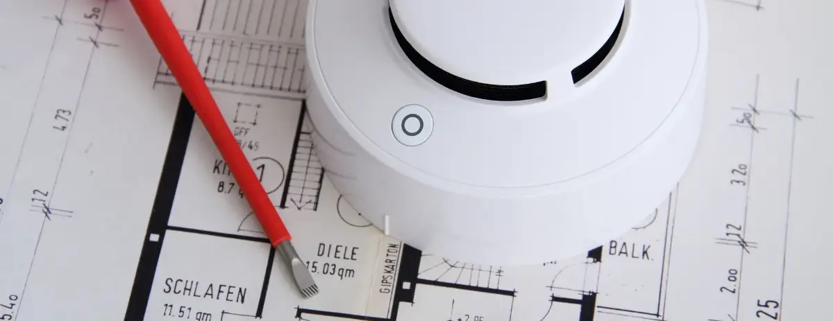 Detailaufnahme eines Brandmelder auf einem Gebäudeblauplan mit rotem Stift zur Markierung.