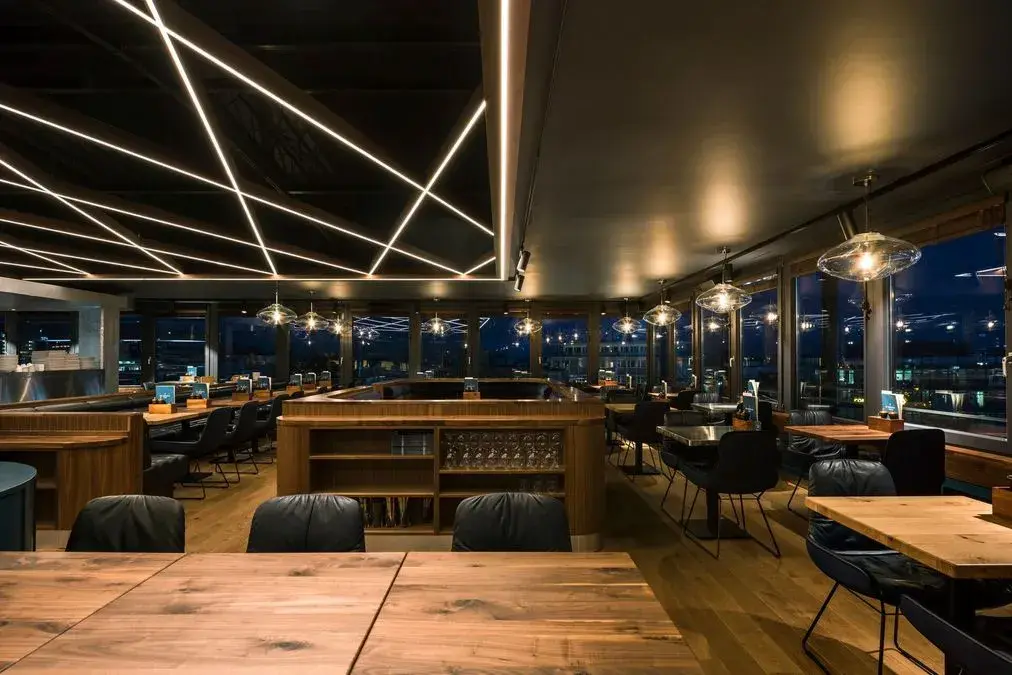 Innenansicht eines stilvollen Restaurants mit warmem Licht und Holzmöbeln.