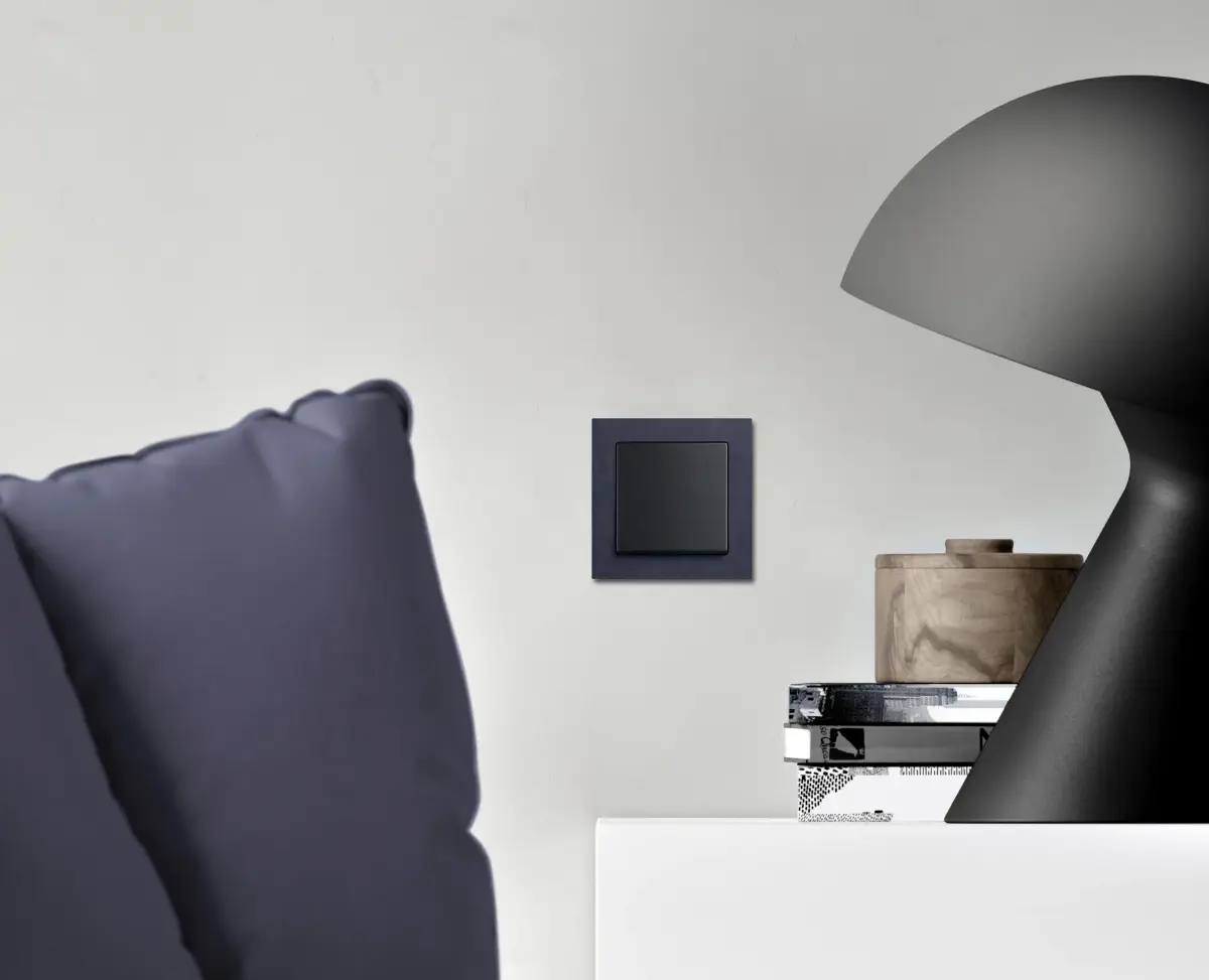 Schwarze Lampe und graues Sofa in modernem Raum.